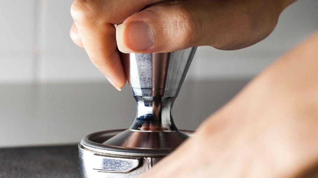 Mano sobre tamper de café