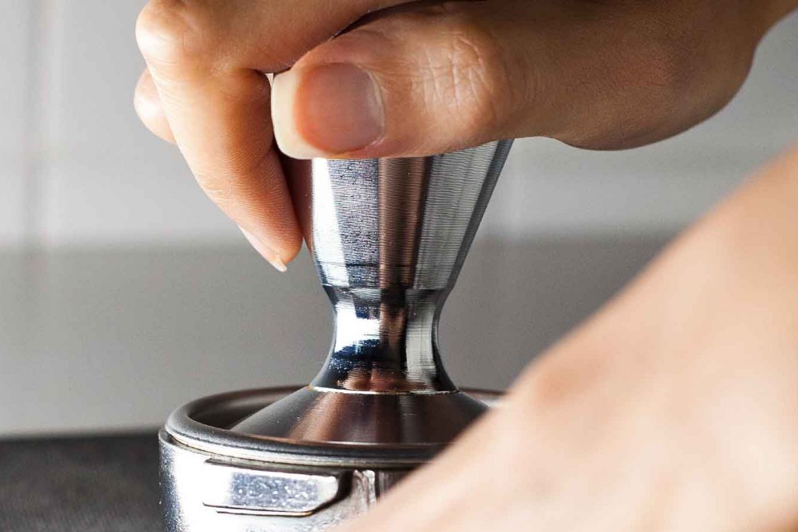 Mano sobre tamper de café