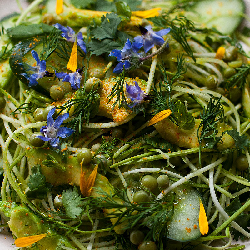 fideos de calabacín con aguacate, flores lobelias, guisantes y pétalos de crisantemo