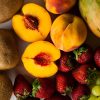 Melocotones, fresas, kiwis, mangos, limones, peras y kiwis sobre mesa blanca