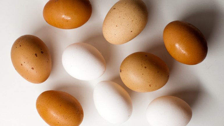 Huevos blancos y marrones sobre mesa blanca