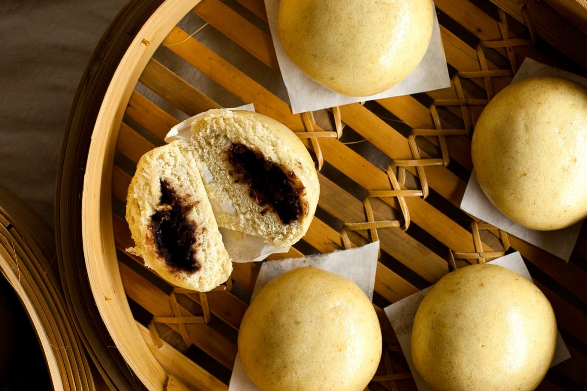 Manju pasteles cerrados y uno cortado a la mitad, sobre vaporera de bambú