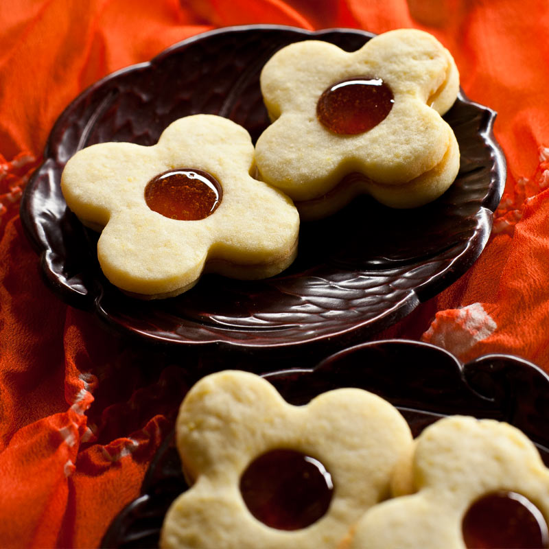 4 galletas de masa sablée en forma de flor sobre platos de laca