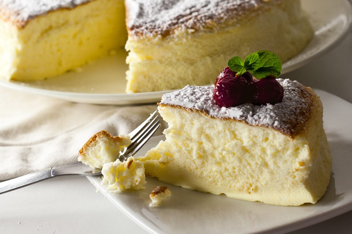 Porción de tarta cheesecake japonés decorada con frambuesas y hojas de menta, cortada con tenedor