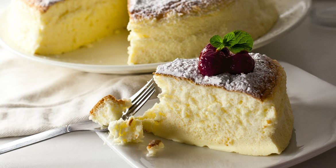 Porción de tarta cheesecake japonés decorada con frambuesas y hojas de menta, cortada con tenedor