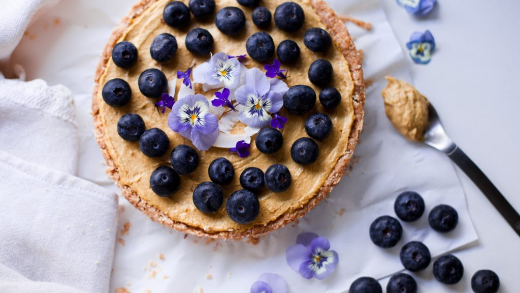 Tarta raw en mesa con cuchara y arándanos al lado