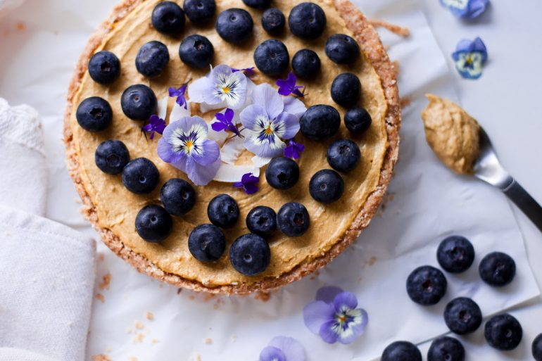 Tarta raw en mesa con cuchara y arándanos al lado