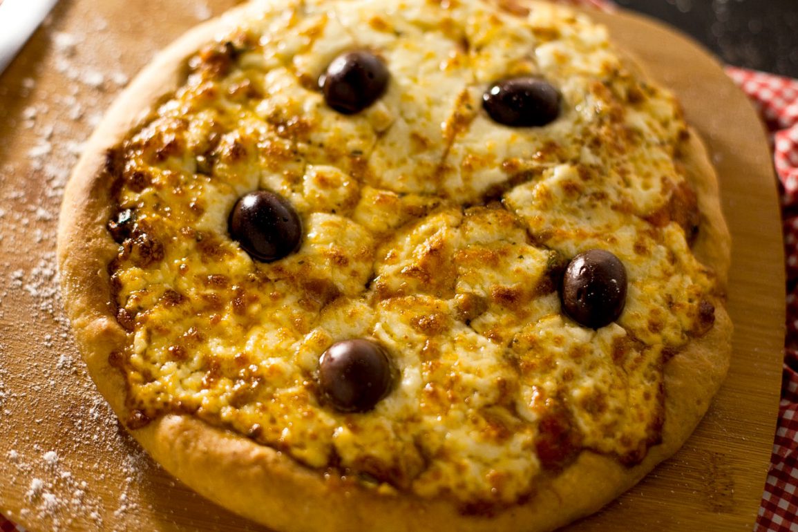 Pizza de queso provolone en tabla de madera sobre mantel de picnic