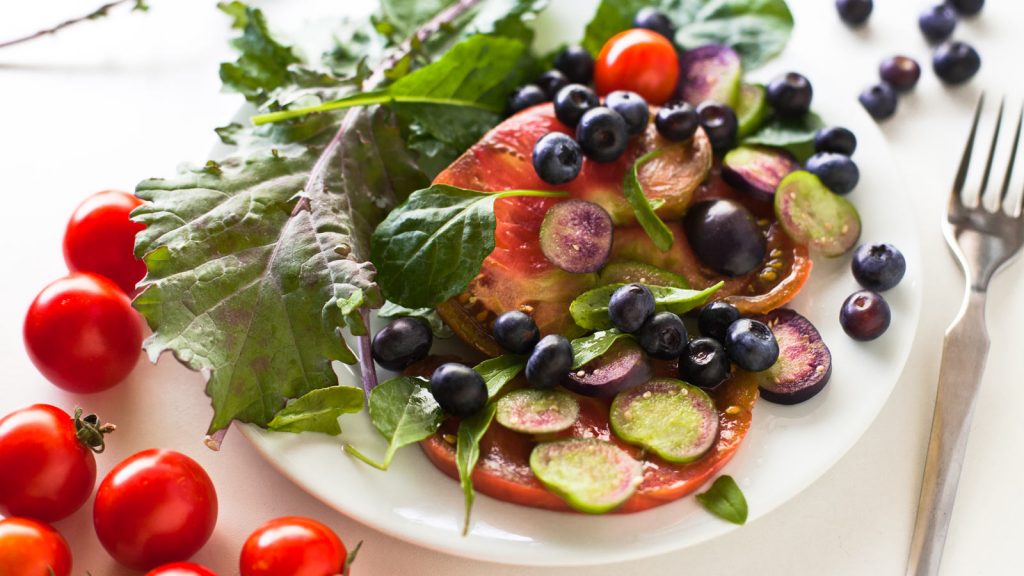 salad with fresh heirloom tomatoes, kale leaves and blueberries, seasoned with lavender salt